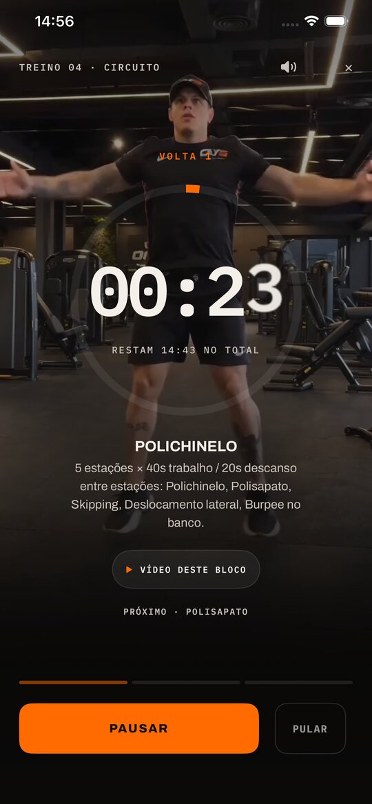 Tela do timer durante um treino de circuito: o cronômetro em 00:23 sobre o vídeo do Carlos, o nome do movimento da vez, Polichinelo, a explicação do bloco e os botões Pausar e Pular.